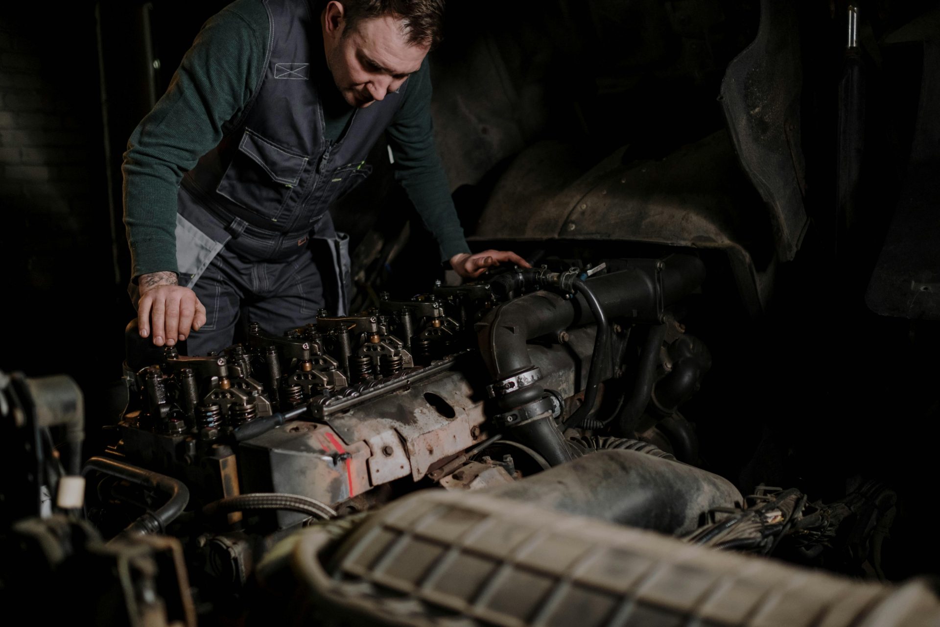 Mecánico enfocado en reparación de motores de vehículos en taller interior.